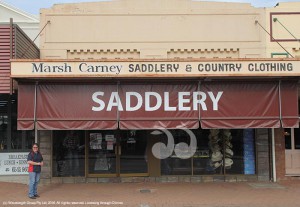 Trish Carney standing beside the large saddlery signage to attract passing trade